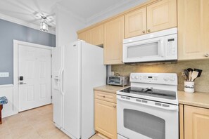 A kitchen with a white refrigerator, microwave, toaster, and oven.