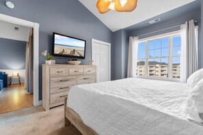 Una camera da letto con un letto, una televisione, un comò e una finestra vista edifici.