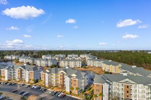 A residential complex with multiple apartment buildings, a parking lot, and a body of water in the background. - Water Views- 5 Beds- Near Broadway @ Beach- Pools (Myrtle Beach)