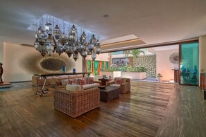 A spacious lobby with wicker furniture, a large chandelier, and a view of the outdoors.