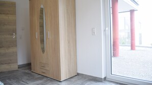 A wooden wardrobe with a mirror, a door, and a window with a view of red pillars. - Hunsr./Reich vacation apartment in the countryside suitable for family a. fitter (Reich)