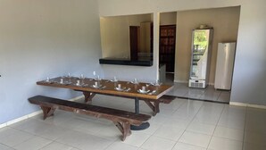Een eetruimte met een lange houten tafel, gedekt voor zes personen, een bankje en een betegelde vloer.