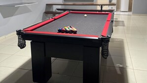 Een biljart met ballen in een kamer met betegelde vloer en een plafondlamp.