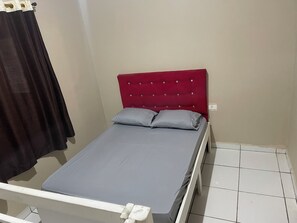 A single bed with a red headboard and two pillows, a white metal frame, and a tiled floor. - Inn with a Pool and Lake (Quatro Barras)