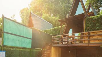 A wooden deck with a swimming pool, a barbecue grill, and a seating area with chairs and a table.