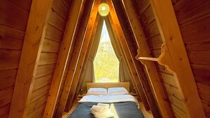 A cozy attic bedroom with a sloped ceiling, a bed with white linens, and a wooden floor. - Natural Life Bungalows Sapanca (Sapanca)