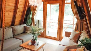 Ein gemütliches Blockhaus-Interieur mit Holzbalkendecke, einer Couch, einem Couchtisch und einem Blumentopf.