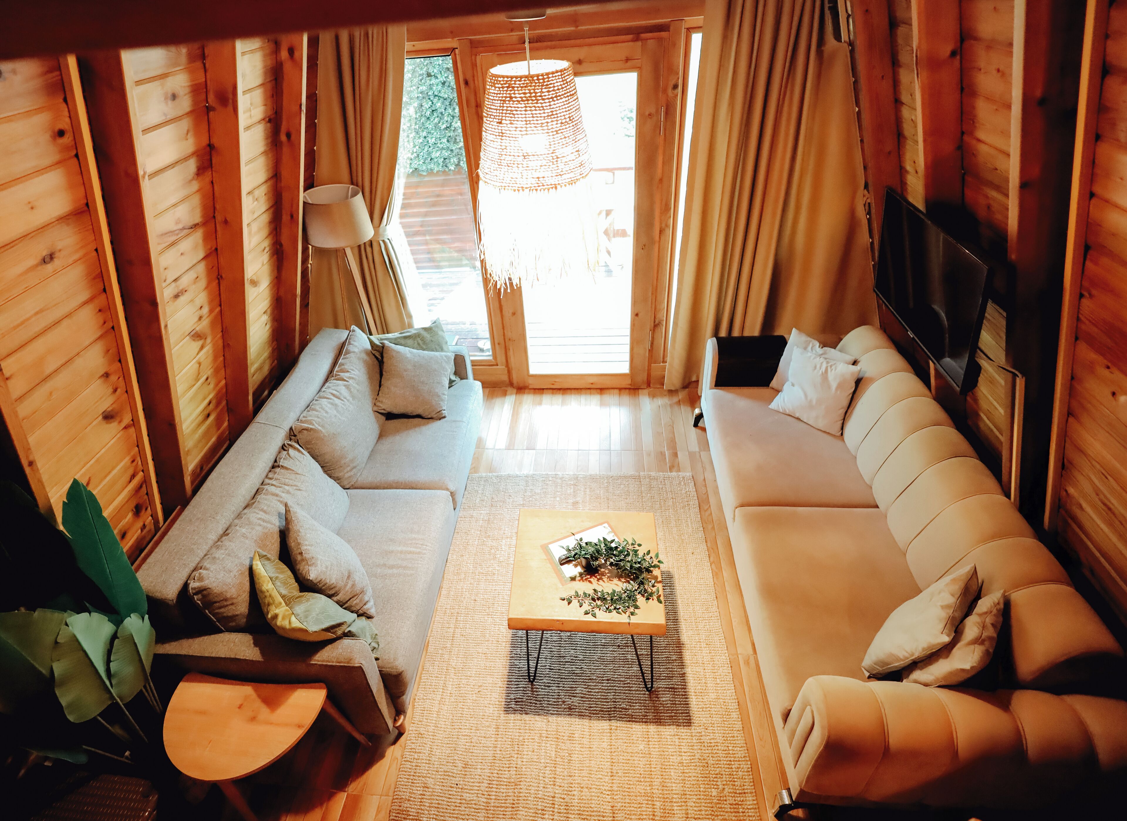 Un acogedor interior de cabaña de troncos con sofá, una mesa de centro y televisor.