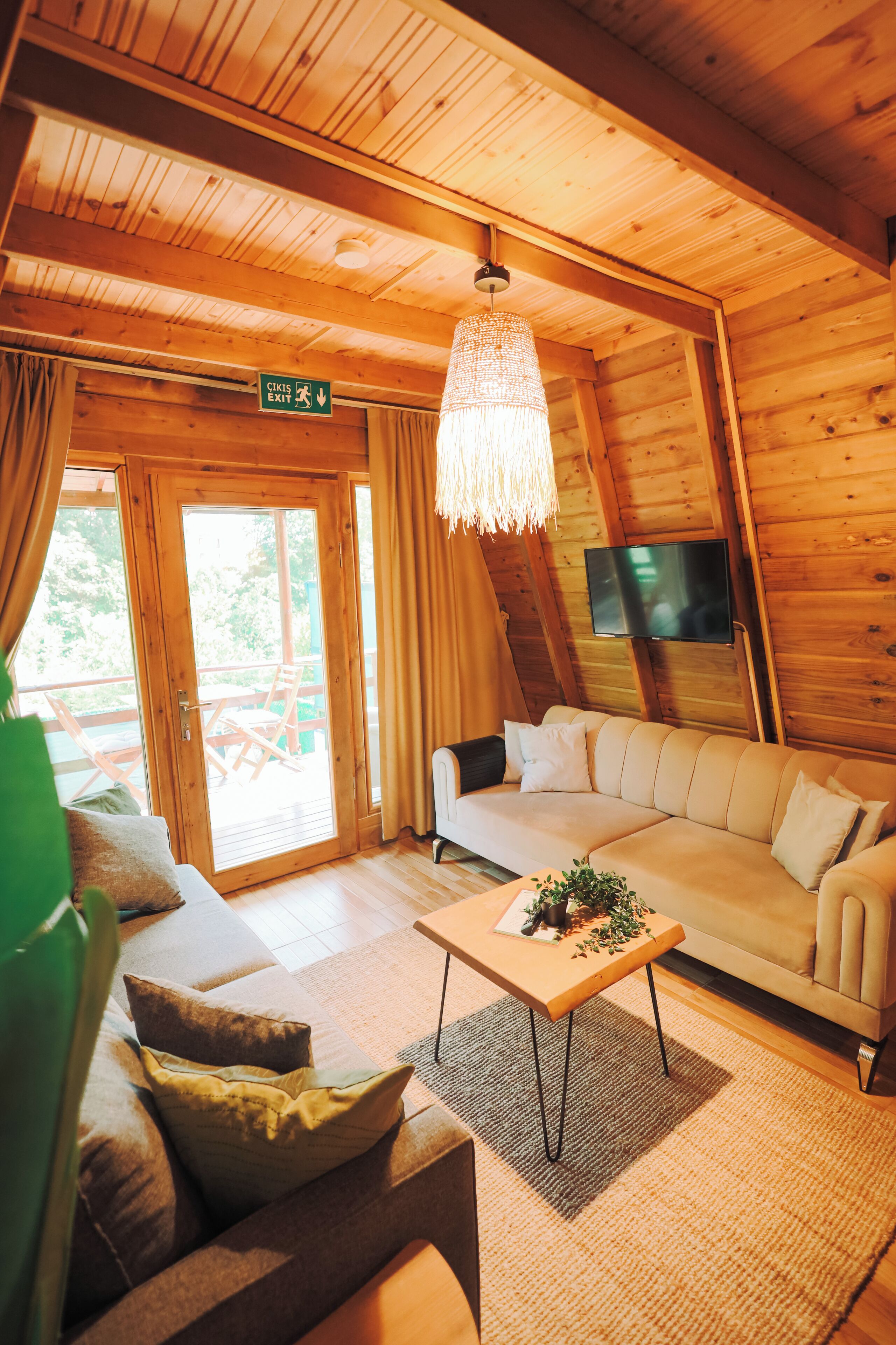 A cozy wooden interior with a sofa, a coffee table, and a TV mounted on the wall.