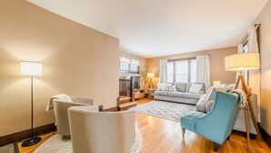 A living room with a sofa, armchairs, a coffee table, and a lamp. - State Ave|Beach|King Beds|Central AC (Alpena)