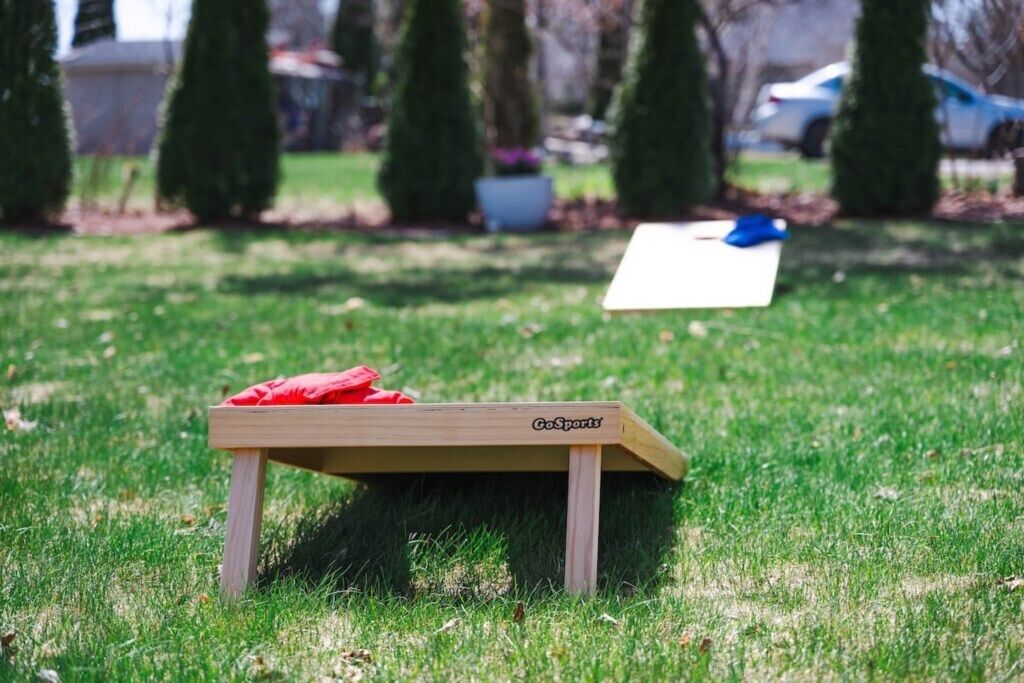 Een GoSports tafel in een groene buitenruimte met een witte tafelkleed en rode kussens.