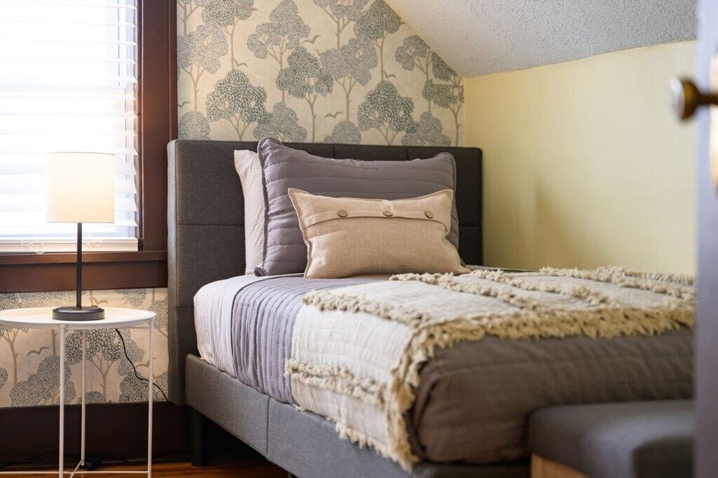 Une chambre à coucher avec un lit, une table de chevet et une fenêtre avec des stores.