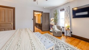 A bedroom with a bed, a ceiling fan, a TV, and a view of a hallway. - State Ave|Beach|King Beds|Central AC (Alpena)