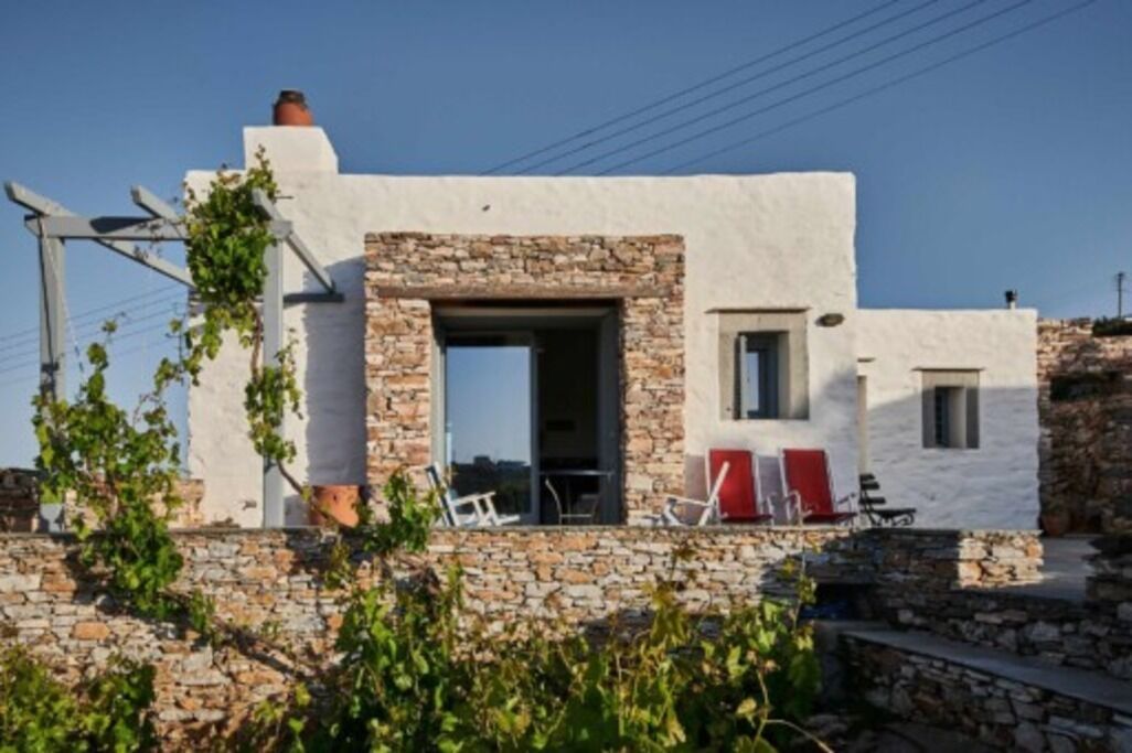 A white building with stone accents, a visible door, and outdoor seating.