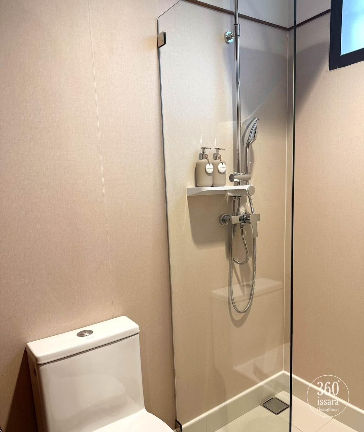 Un bagno moderno con cabina doccia in vetro, un water e uno scaffale con articoli da toilette.
