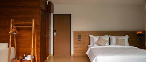 A modern hotel room with a wooden headboard, a large bed, a wooden wardrobe, and a ceiling fan.