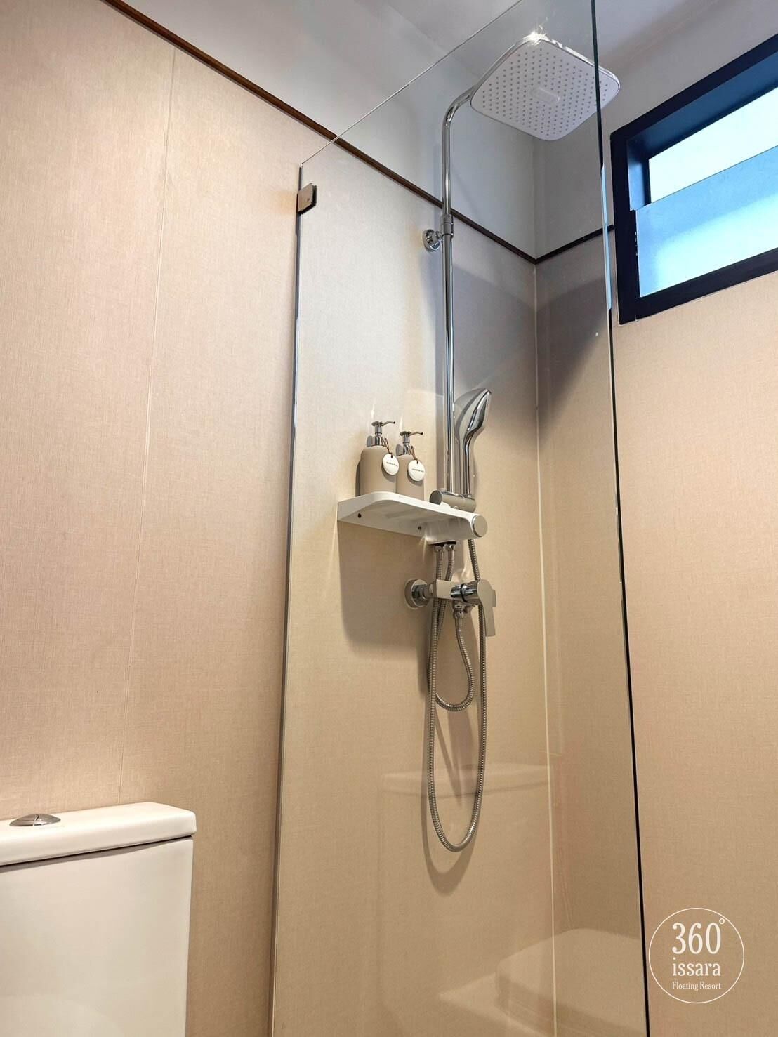 Et moderne badeværelse med bruseniche, toilet og hylder med toiletartikler.