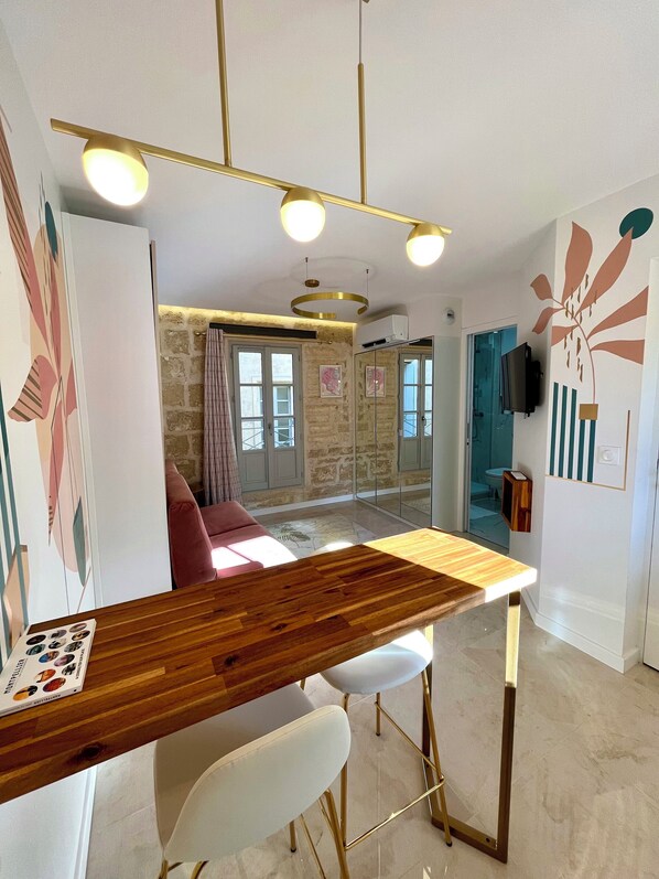 Una cocina moderna con encimera de madera, sillas blancas y una lámpara colgante.