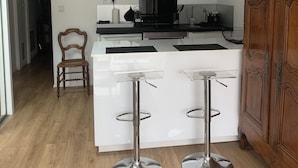 Uma cozinha moderna com armários brancos, eletrodomésticos de aço inoxidável e uma área de jantar em madeira.