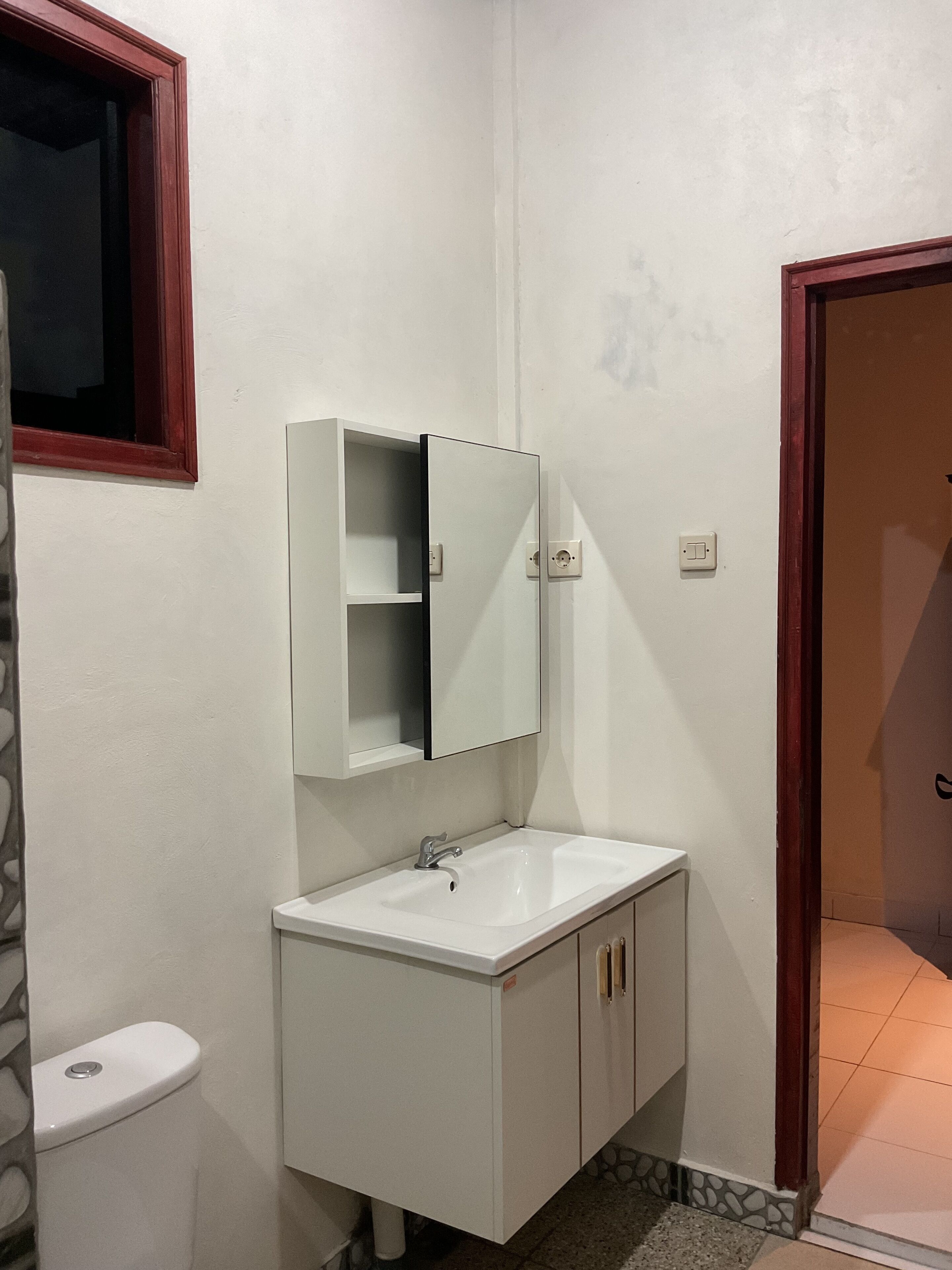 Une salle de bain avec un lavabo blanc, un miroir au-dessus et des toilettes.