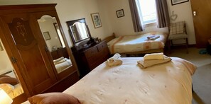 Una habitación de hotel con una cama grande, un aparador, un espejo y una ventana con cortinas.