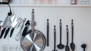 A kitchen with a stove, sink, and various utensils and cookware hanging on the wall. - Das Nordberg Apartments (Garmisch-Partenkirchen)