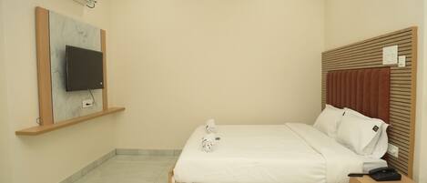A neatly arranged bedroom with a bed, bedside table, and a mounted TV.