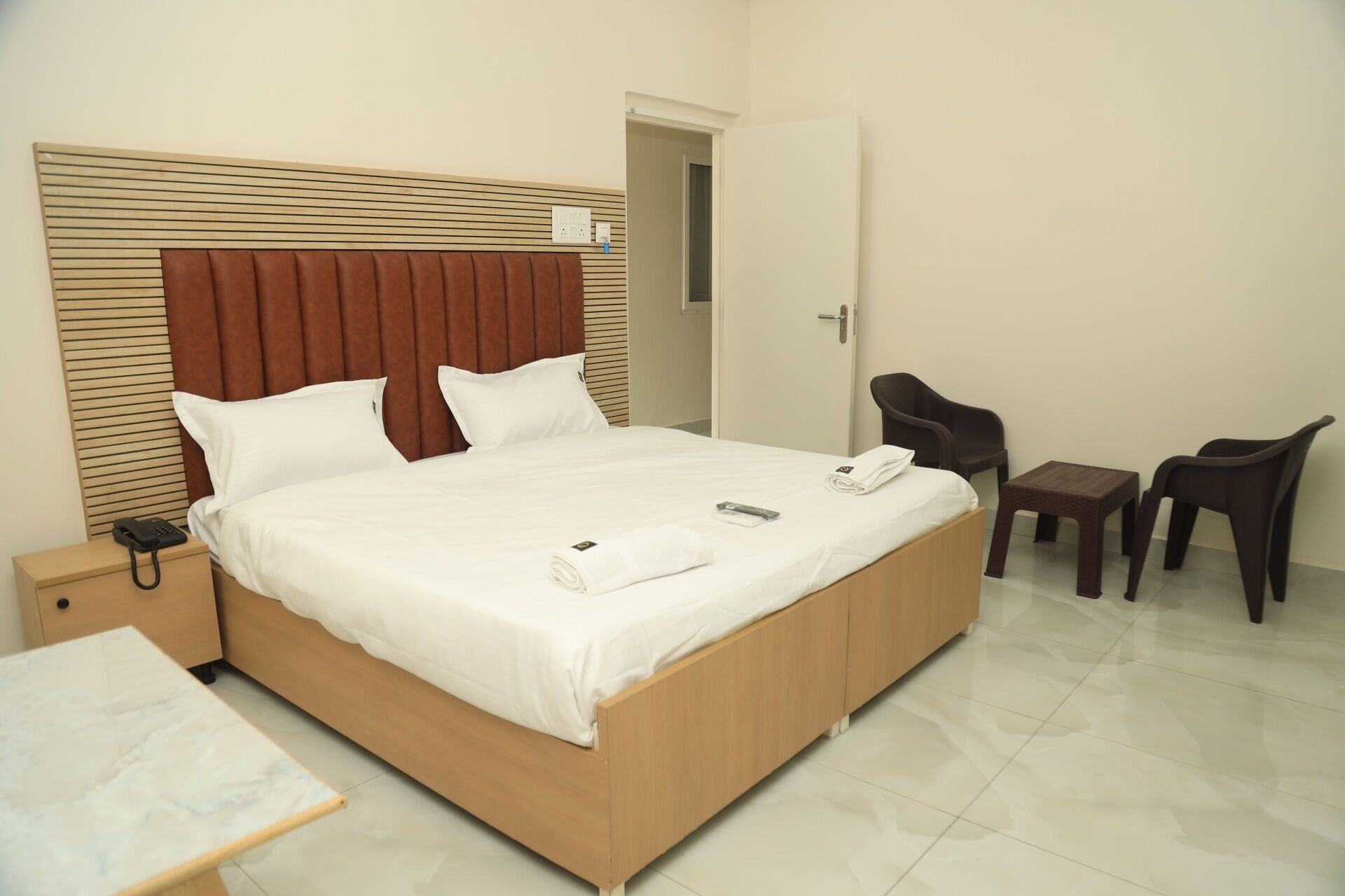 Una habitación de hotel con una cama grande, una mesita de noche, una silla y una pequeña mesa.