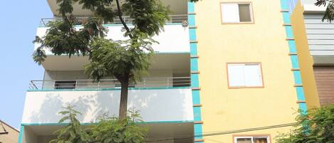 A multi-story building with a sign for 'Vajaraja Exotica' indicating a coffee shop and luxury rooms.