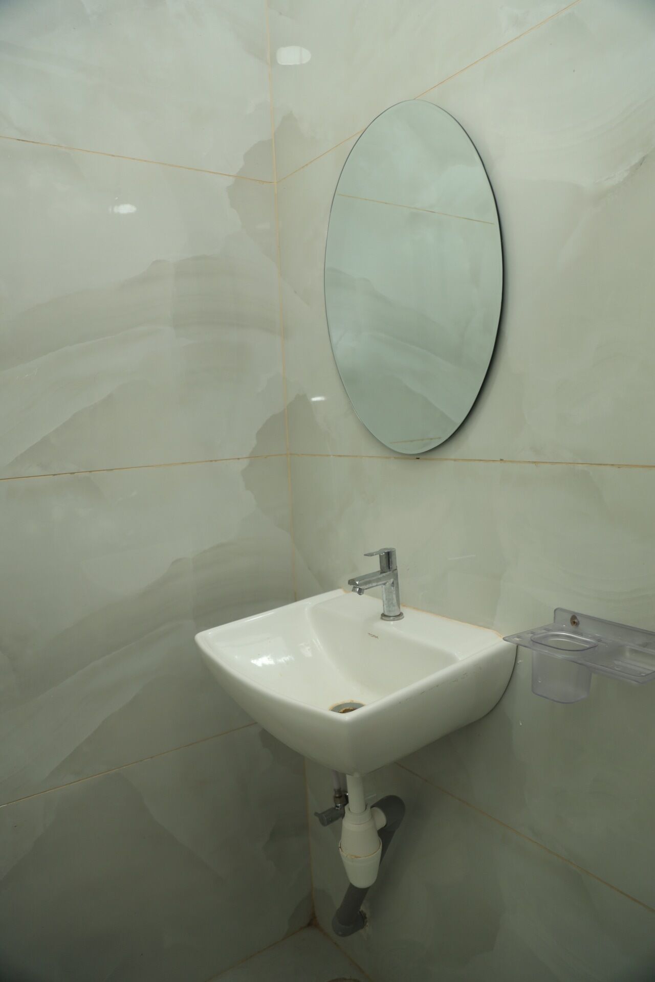 A bathroom with a white sink, a mirror, and a soap dispenser.
