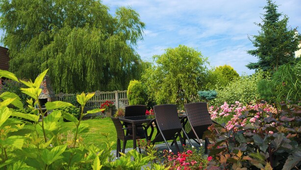 A garden patio with wicker chairs and a stone fireplace. - Agroturystyka Pod Jesionem  (Wladyslawowo)