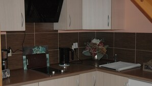 A kitchen with wooden cabinets, a coffee maker, a sink, and a vase with flowers. - Agroturystyka Pod Jesionem  (Wladyslawowo)