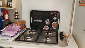 A kitchen with a gas stove, a black tray with a cartoon character, and various kitchen items on the counter. - La bretagne ça gagne vous!! near Vannes Sarzeau STgildas de ruys (Surzur)