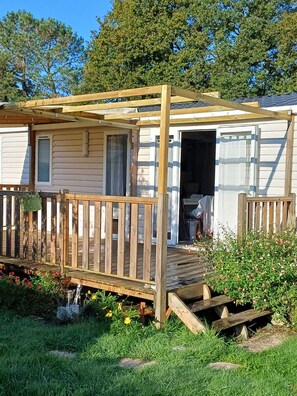 Une maison mobile dotée d’une terrasse en bois et d’un porche couvert.
