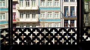 A view through a window of a building with multiple floors, balconies, and a tiled roof. - Boutique Rentals-SãO*bEnTo Ribeira Apt (Porto)