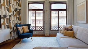 A living room with a blue armchair, a white sofa, and a patterned wall. - Boutique Rentals-SãO*bEnTo Ribeira Apt (Porto)