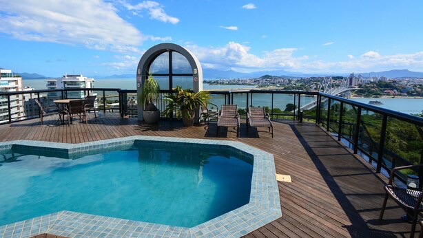 A rooftop pool area with a view of the city and a bridge.