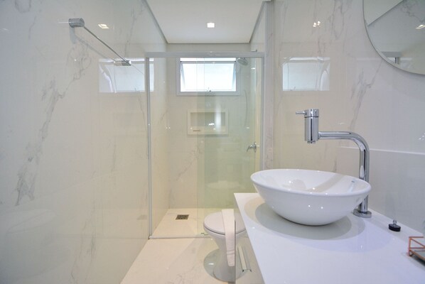 A modern bathroom with a glass-enclosed shower, a white sink, and a large mirror.