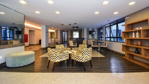 A modern interior with a seating area featuring patterned chairs, a central table, and a wooden bookshelf.
