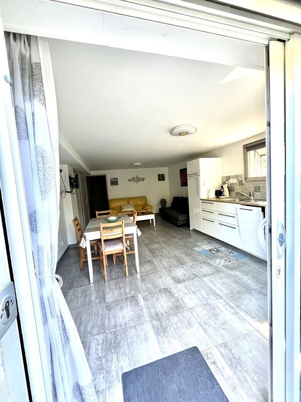 A compact living space with a dining area, a sofa, a kitchen, and a sliding door.