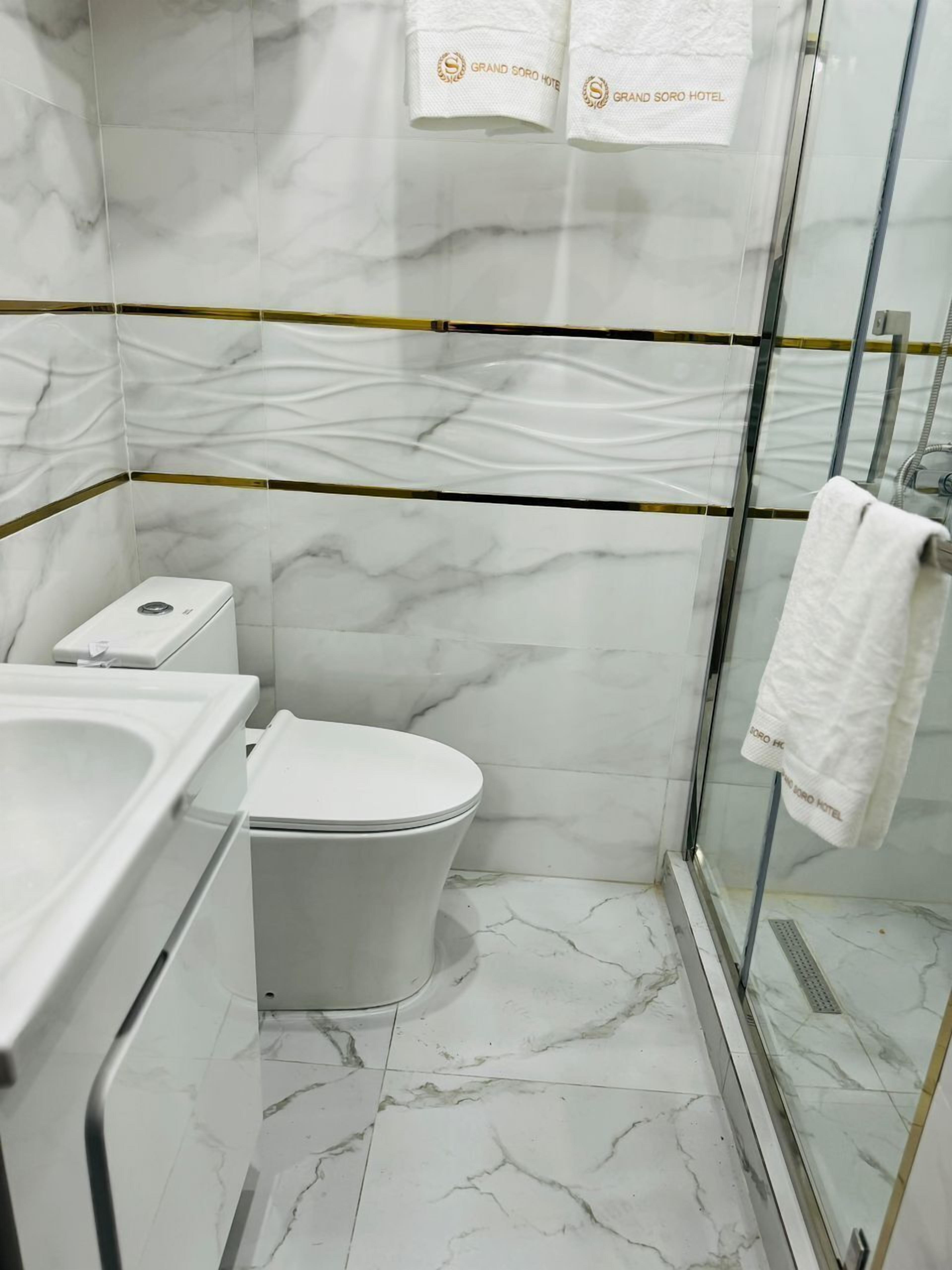 A bathroom with a toilet, sink, and glass shower enclosure.