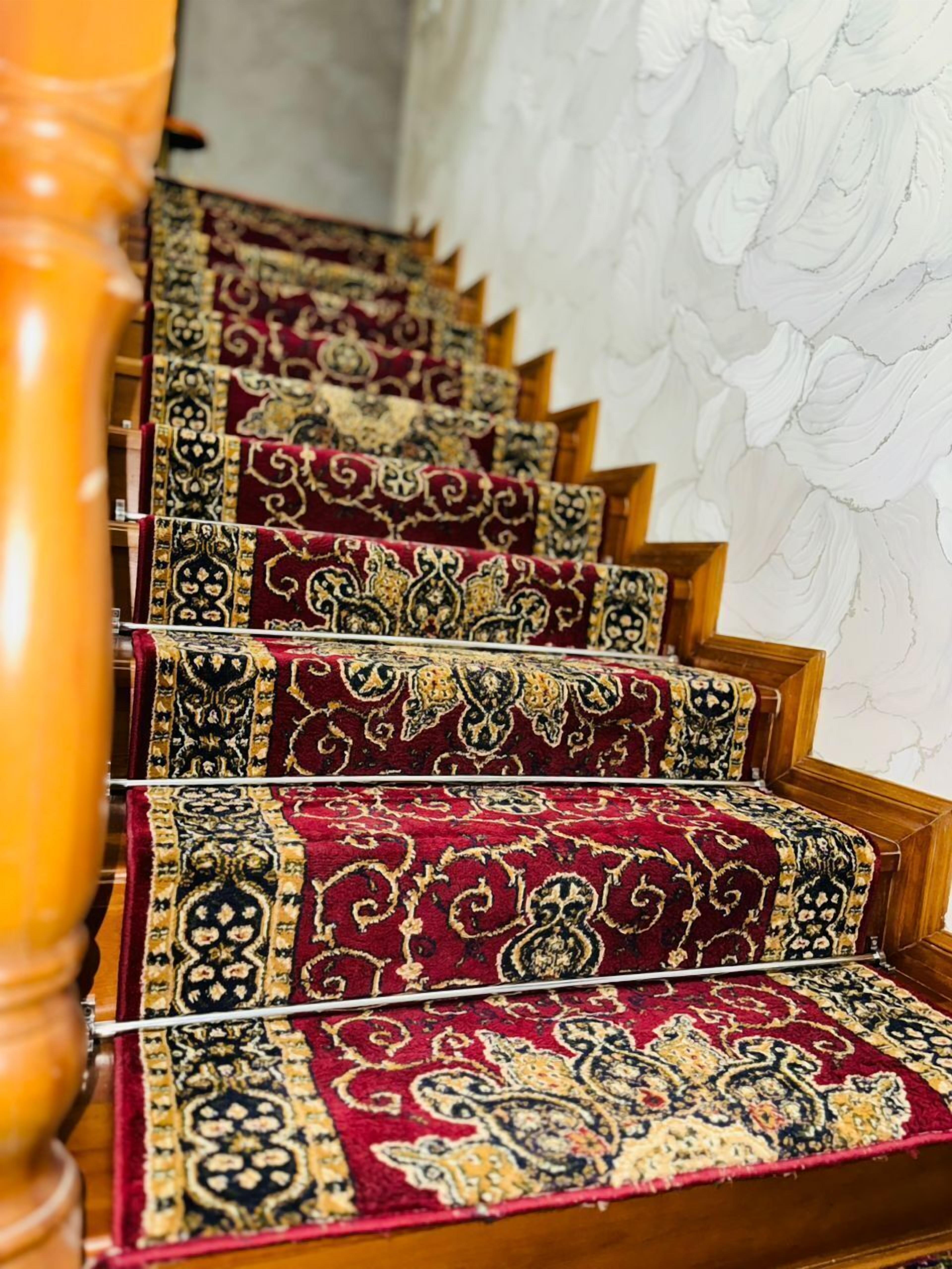 A staircase with ornate red carpets and wooden handrails.