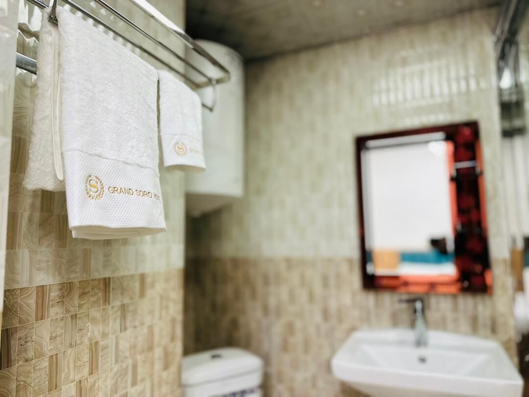 A bathroom with a tiled wall, a sink, and a mirror.