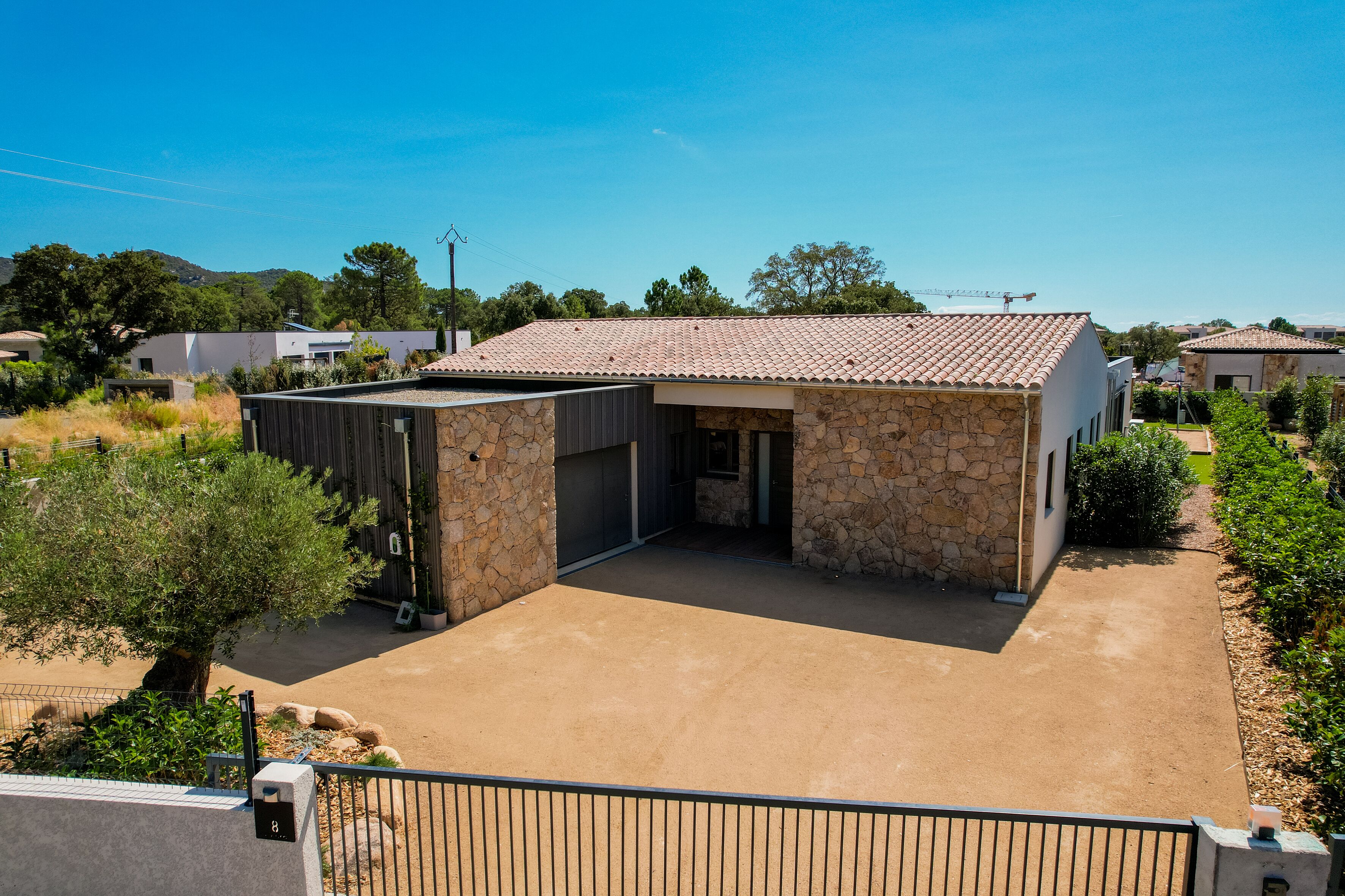 A modern house with a stone facade, a tiled roof, and a paved patio area.