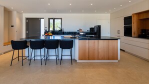 Une cuisine moderne dotée d’un îlot central, de tabourets de bar et d’appareils électroménagers intégrés.