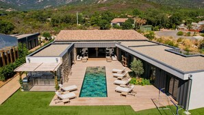 Une maison moderne dotée d’une piscine, d’une cuisine extérieure et d’un espace détente.