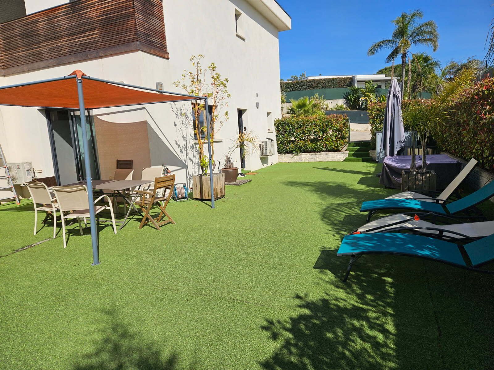 Eine Terrasse mit Tisch und Stühlen, Sonnenschirm und Liegestühlen.