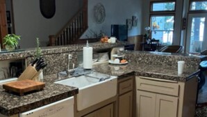 A kitchen with a granite countertop, wooden cabinets, a dishwasher, and a wooden floor. - Beautiful Lake Front Home on Lake Almanor. (Westwood)