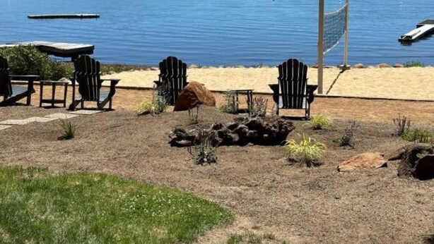 A lakeside patio with Adirondack chairs, a fire pit, and a view of the water and mountains. - Beautiful Lake Front Home on Lake Almanor. (Westwood)