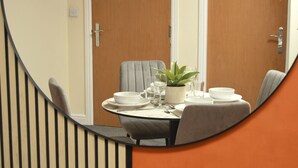 Un comedor con una mesa redonda para cuatro personas, una planta en maceta y un diseño de silla moderno.